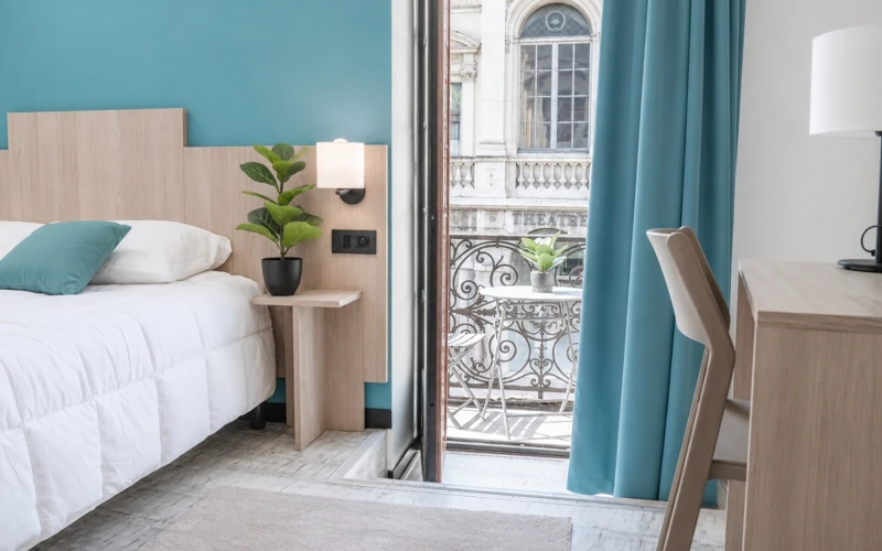 Chambre Loge avec vue de l'Hôtel des Artistes à Chambéry avec lit double, coin bureau et balcon donnant sur le théâtre Charles Dullin