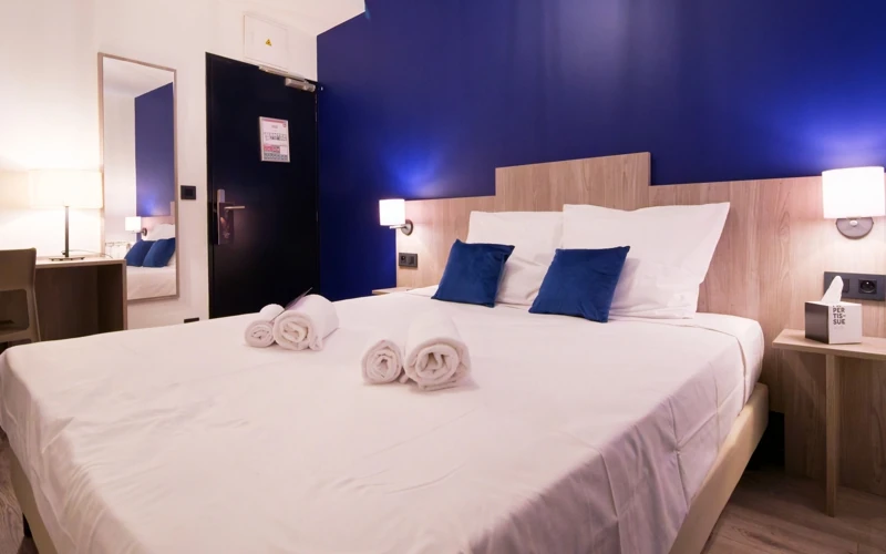 Chambre solo avec lit double et murs bleu nuit à l’Hôtel des Artistes à Chambéry