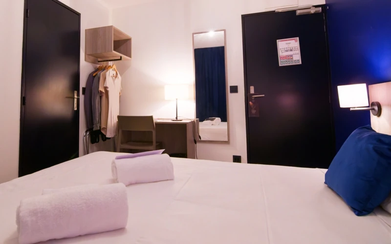 Vue de la chambre Solo de l'Hôtel des Artistes avec lit double, espace de travail, petite penderie et miroir