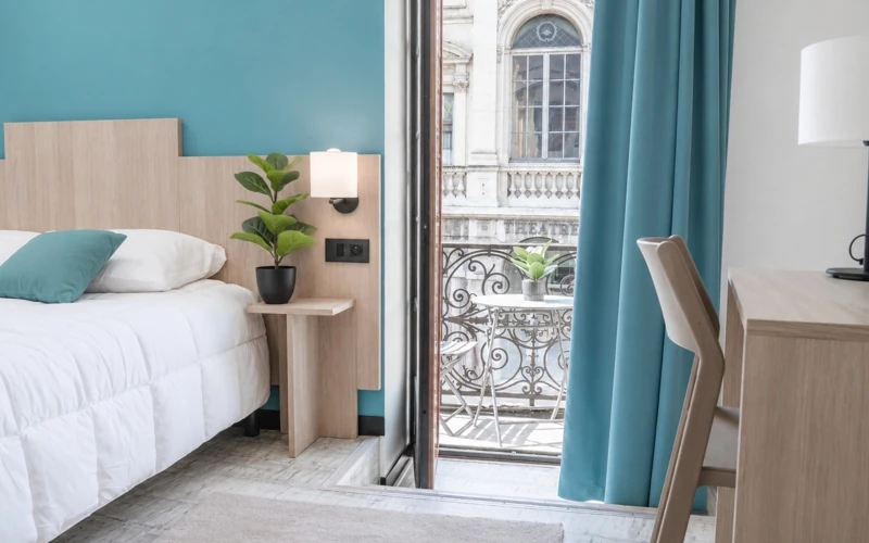 Vue d'ensemble de la chambre Loge Duo avec lit double, chevet et balcon à l'Hôtel des Artistes à Chambéry