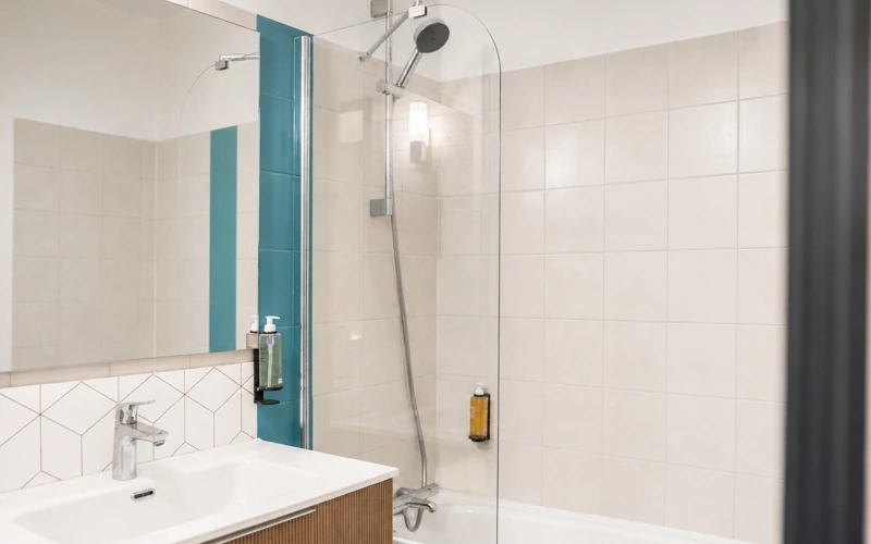 Salle de bain moderne de la Loge Duo à l'Hôtel des Artistes avec meuble vasque et baignoire à paroi vitrée